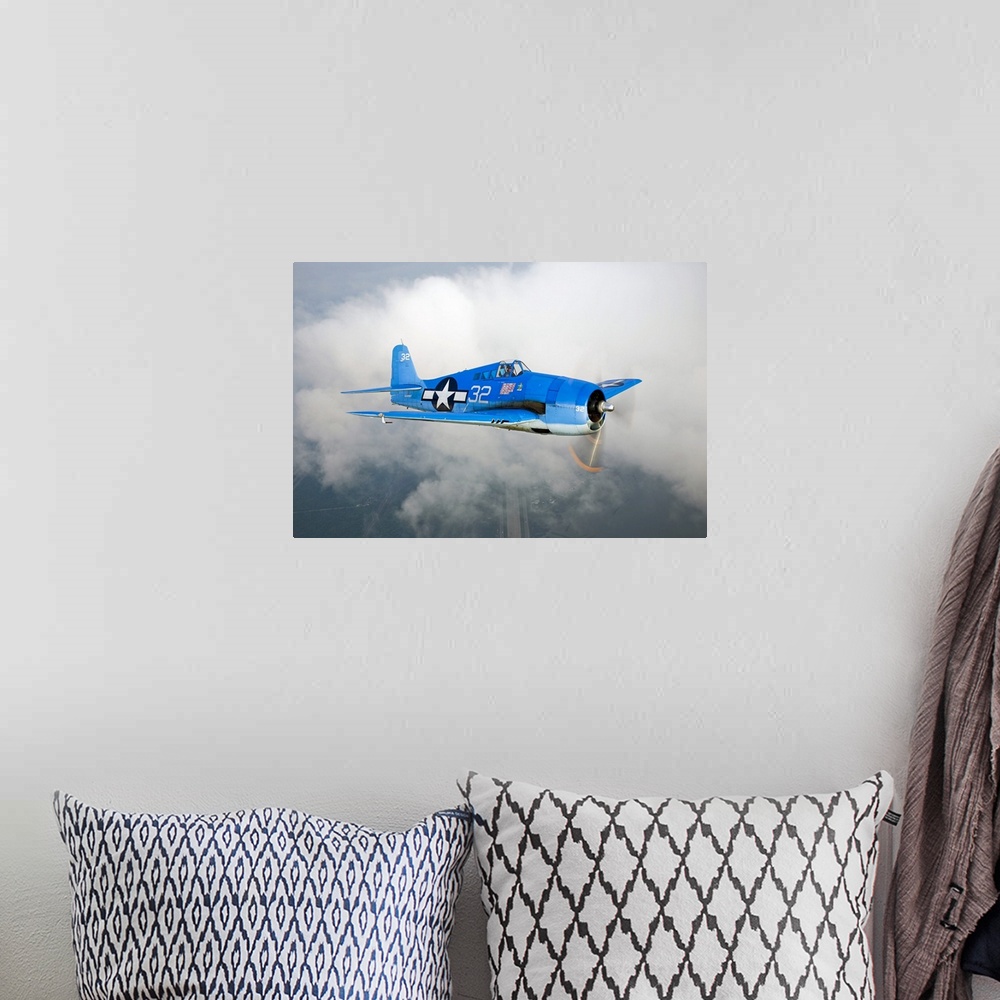 A bohemian room featuring A vintage military aircraft is photographed high in the sky with a large cloud just behind it.