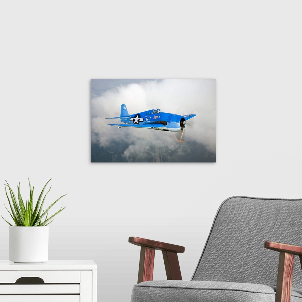 A modern room featuring A vintage military aircraft is photographed high in the sky with a large cloud just behind it.