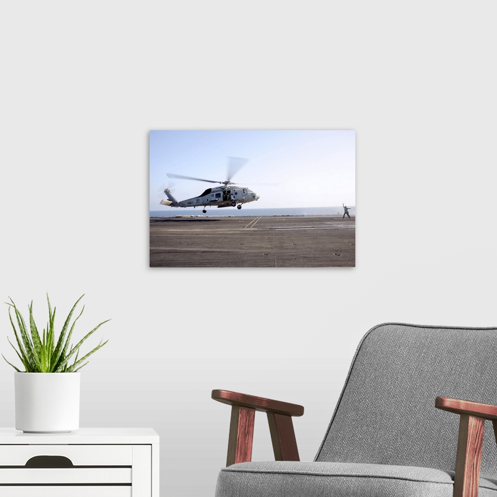 A modern room featuring A helicopter landing signalman directs an SH-60F Sea Hawk.