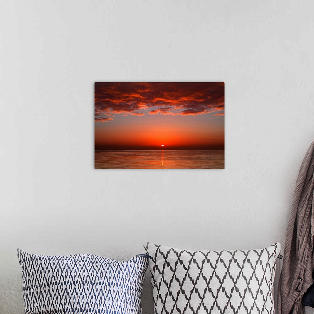 A bohemian room featuring A layer of clouds is lit by the rising sun over Rio de la Plata, Buenos Aires, Argentina.
