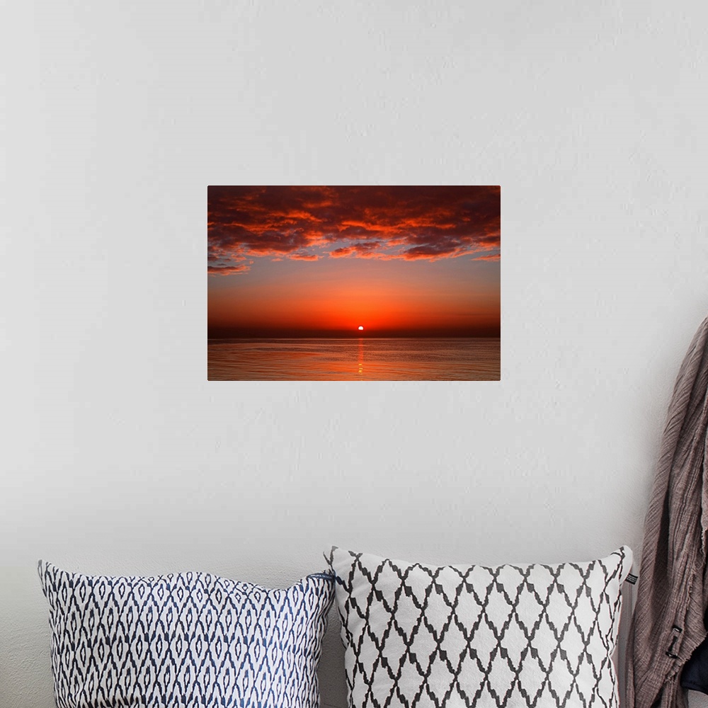 A bohemian room featuring A layer of clouds is lit by the rising sun over Rio de la Plata, Buenos Aires, Argentina.