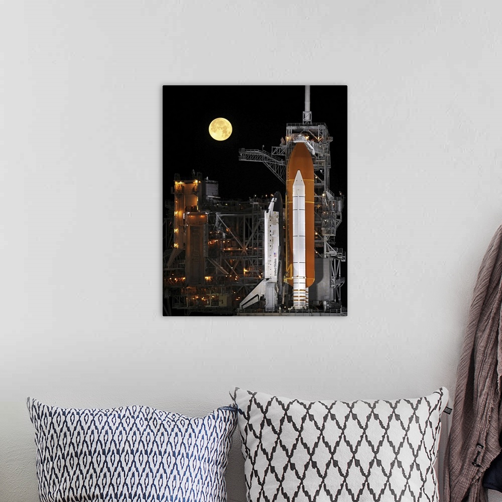 A bohemian room featuring A nearly full Moon sets as Space Shuttle Discovery sits atop the launch pad