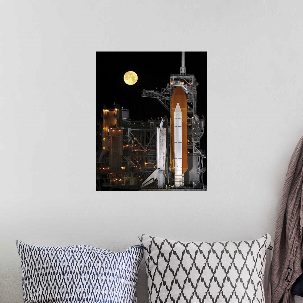 A bohemian room featuring A nearly full Moon sets as Space Shuttle Discovery sits atop the launch pad