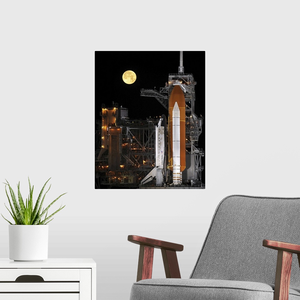 A modern room featuring A nearly full Moon sets as Space Shuttle Discovery sits atop the launch pad