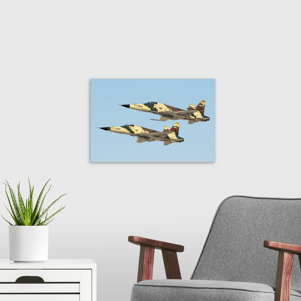 A modern room featuring A pair of Islamic Republic of Iran Air Force HESA Saegheh I aircraft in flight.