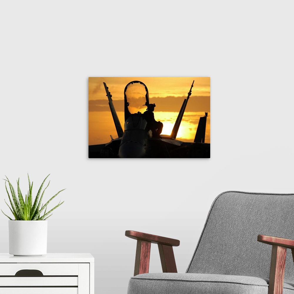 A modern room featuring A plane captain enjoys a sunset from atop an F/A-18 Hornet.