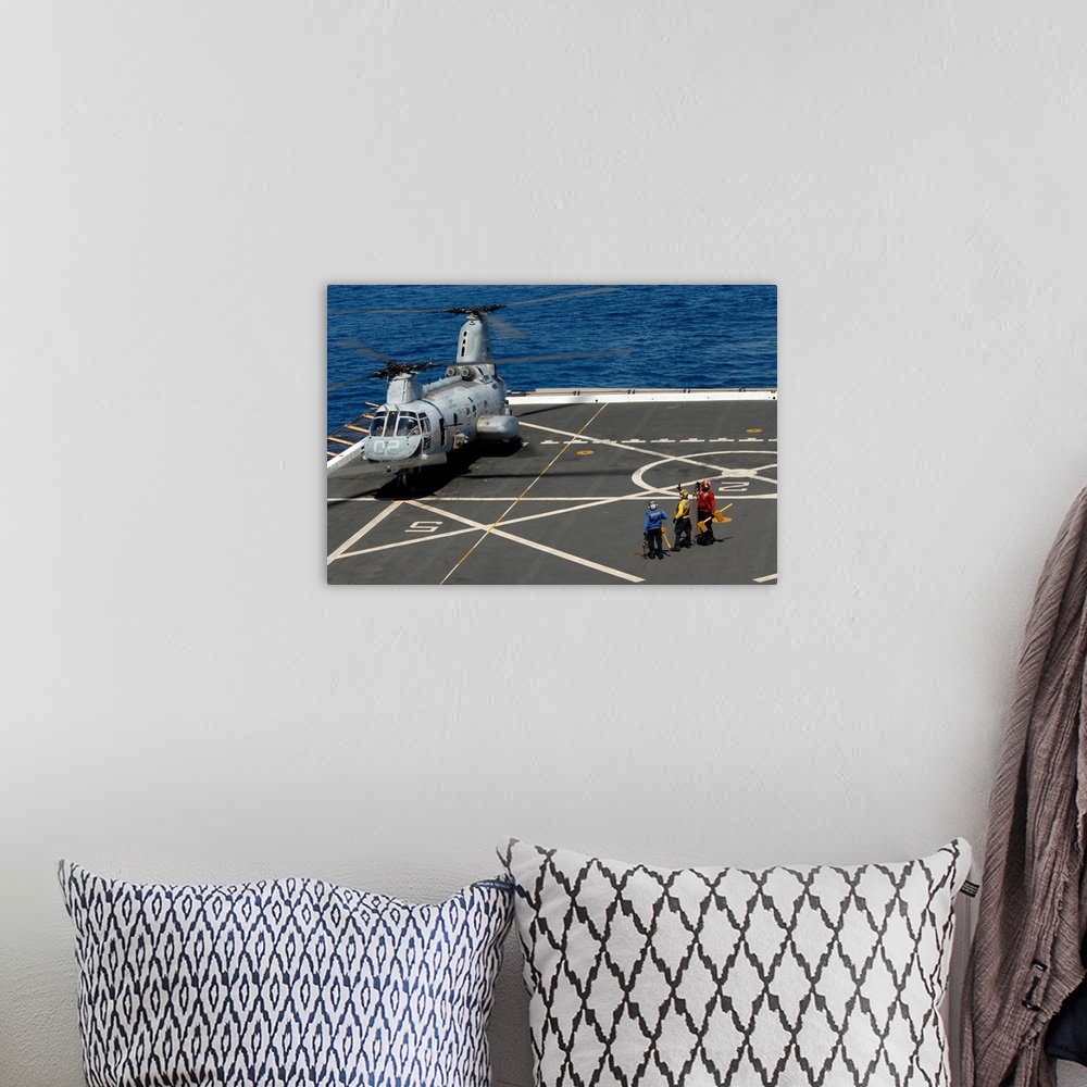 A bohemian room featuring A plane captain signals to a CH-46E Sea Knight helicopter.