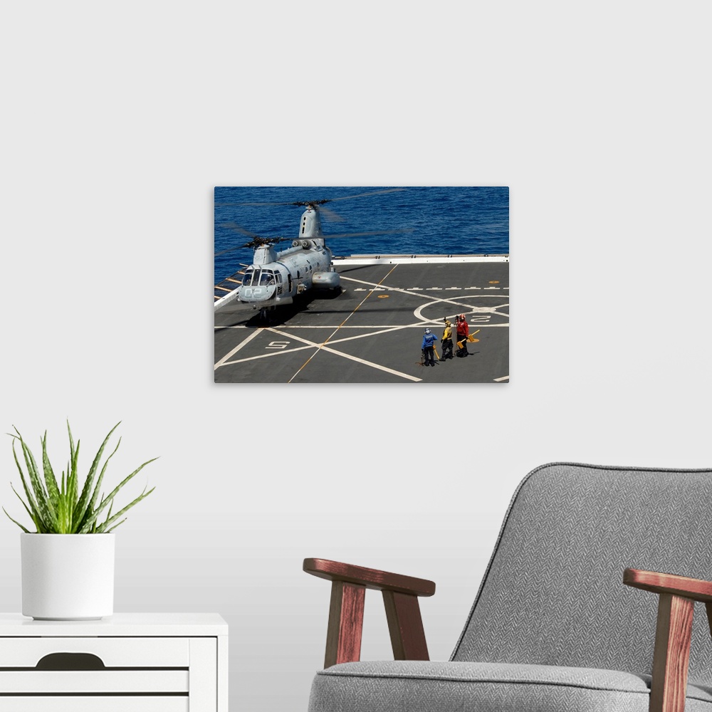 A modern room featuring A plane captain signals to a CH-46E Sea Knight helicopter.
