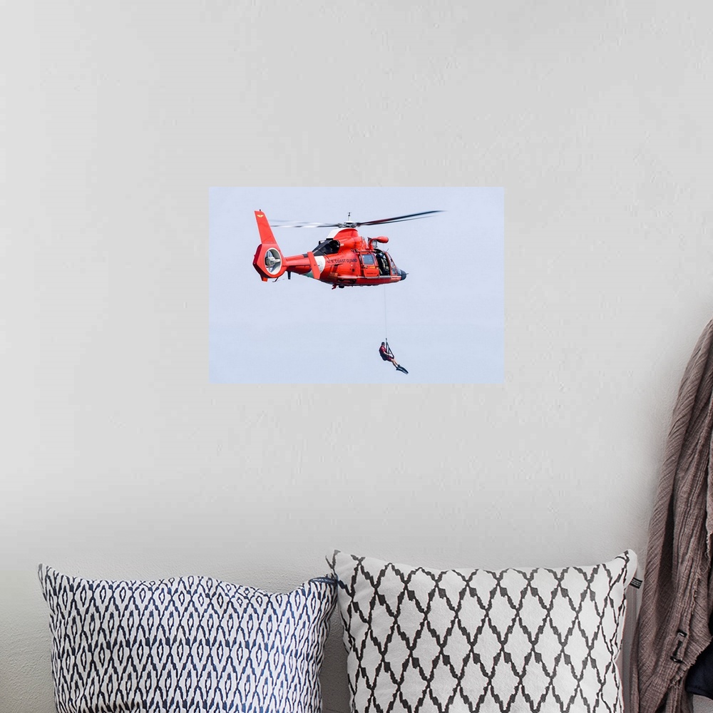 A bohemian room featuring A rescue swimmer is lowered from a U.S. Coast Guard HH-65 Dolphin helicopter.