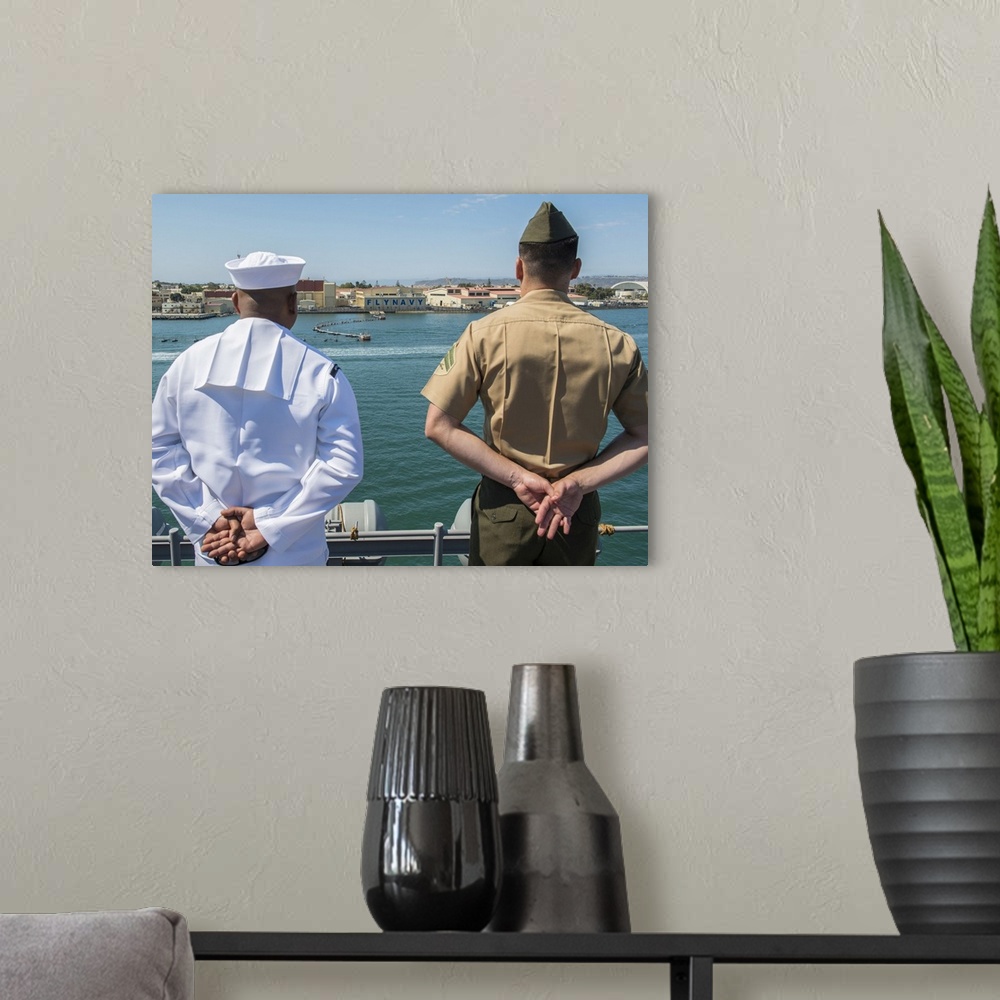 A modern room featuring San Diego, California, August 23, 2013 - A Sailor and Marine man the rails aboard the amphibious ...
