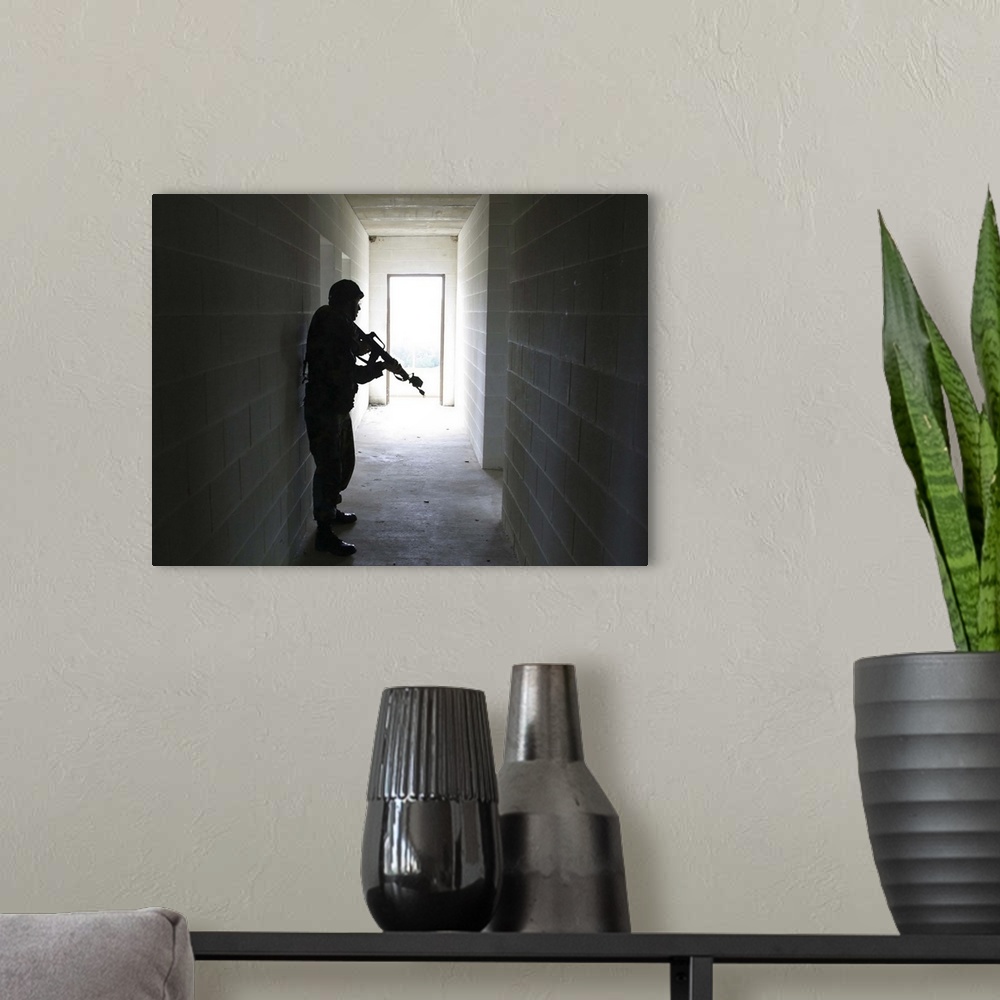 A modern room featuring A soldier clears a hallway at a Military Operation in Urban Terrain training facility