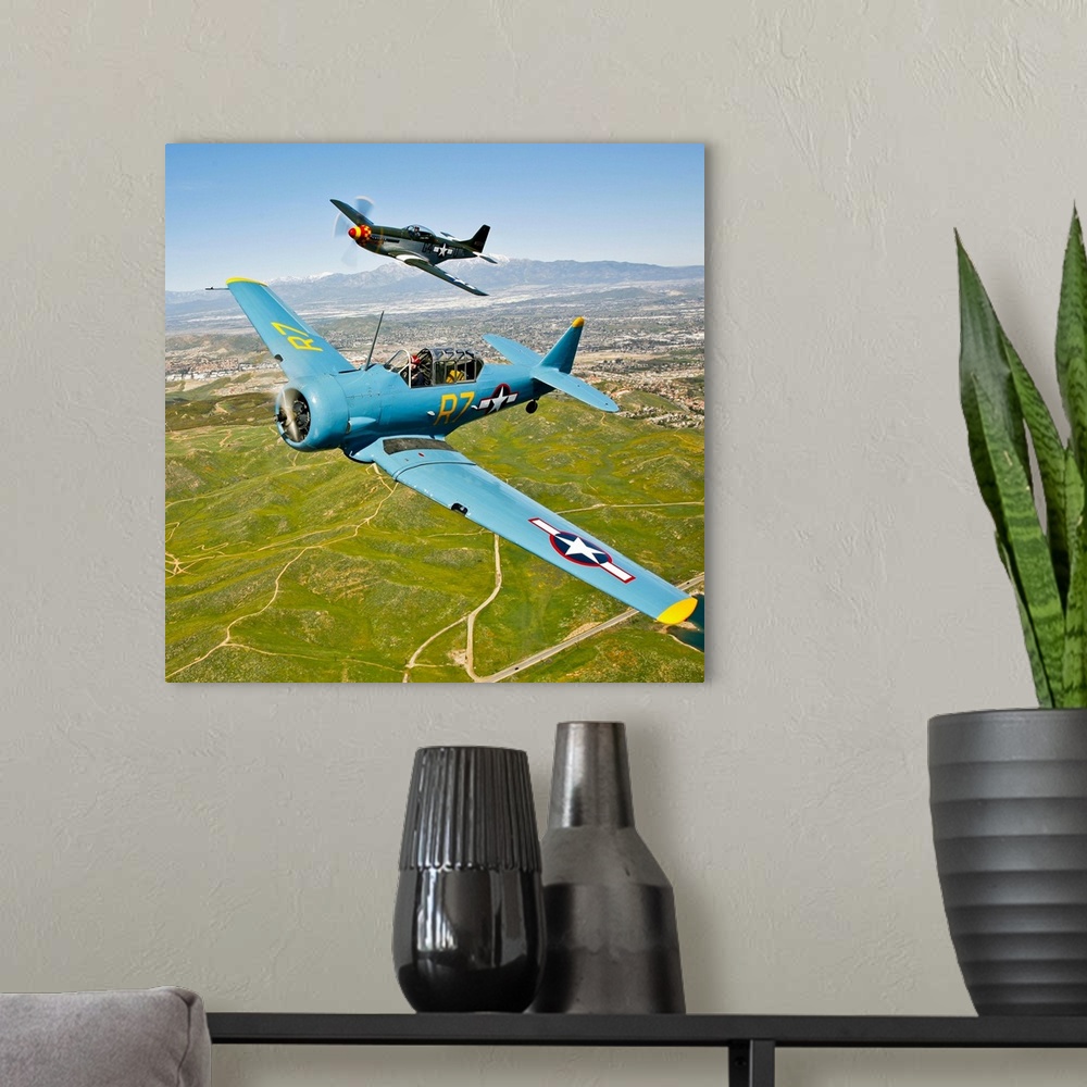 A modern room featuring A North American T-6 Texan and a P-51D Mustang in flight over Chino, California.