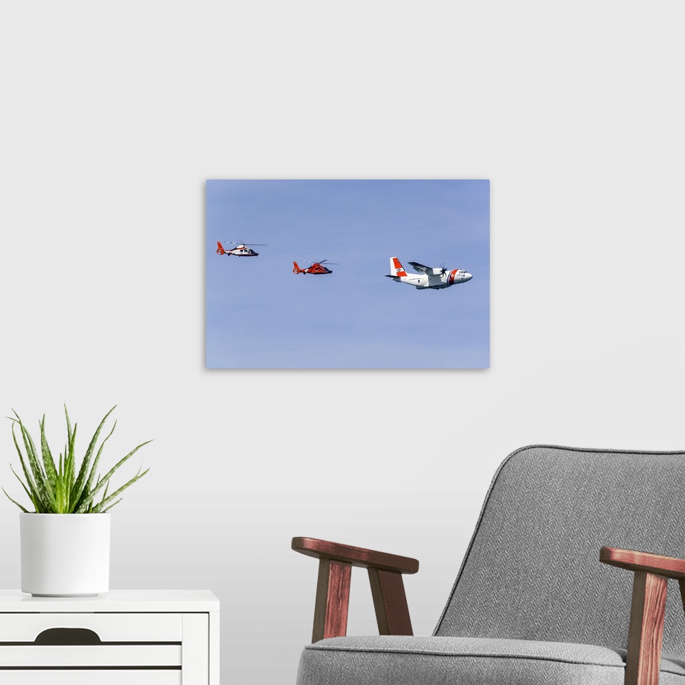 A modern room featuring A U.S. Coast Guard C-27J makes a flypast in formation with two Eurocopter MH-65 Dolphin helicopte...
