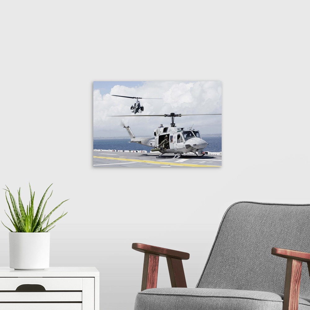 A modern room featuring A UH-1N Huey and an AH-1W Super Cobra land on flight deck of USS Essex.