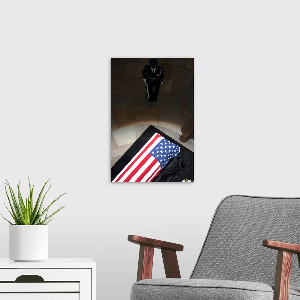 A modern room featuring A U.S. Air Force Honor Guardsman stands watch over the casket.