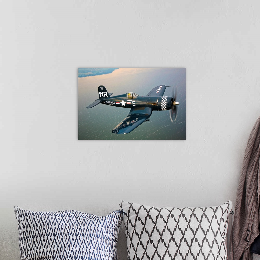 A bohemian room featuring Horizontal photograph of a Vought F4U-5 Corsair in flight over a large body of water, the coastli...