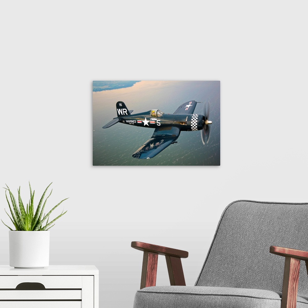 A modern room featuring Horizontal photograph of a Vought F4U-5 Corsair in flight over a large body of water, the coastli...
