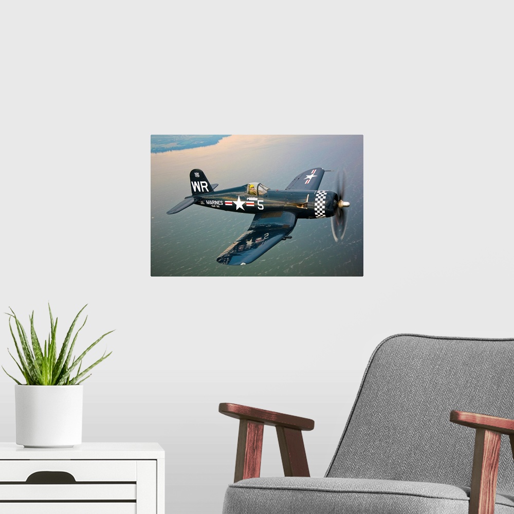 A modern room featuring Horizontal photograph of a Vought F4U-5 Corsair in flight over a large body of water, the coastli...
