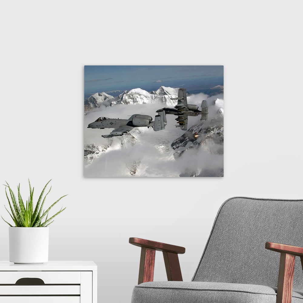 A modern room featuring Big, horizontal photograph of two A10 Thunderbolt IIs flying through the clouds, above snow cover...