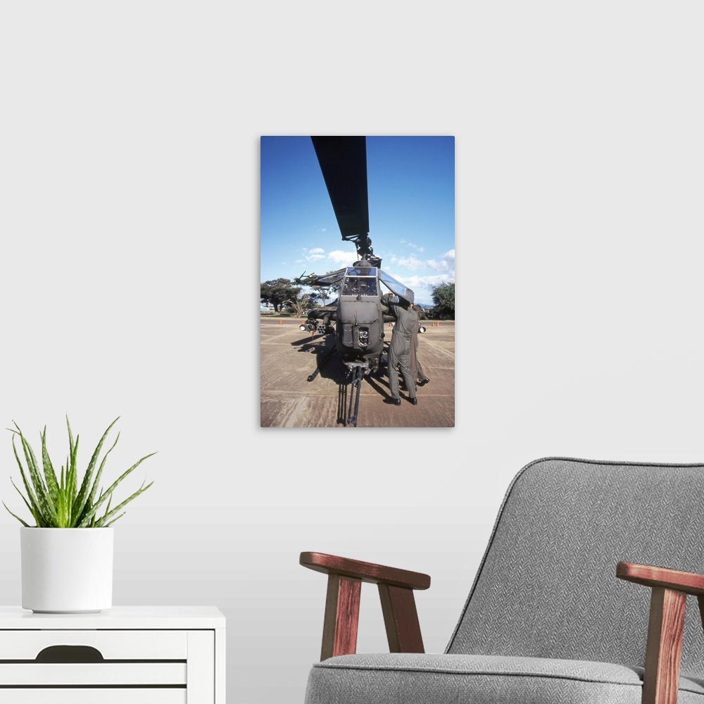 A modern room featuring Air crewmen secure an AH1 Cobra attack helicopter