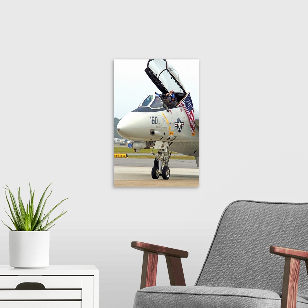 A modern room featuring Air crewmen wave from their F14D Tomcat as they taxi