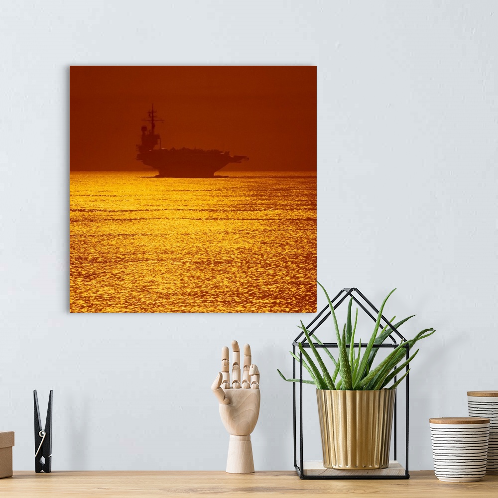 A bohemian room featuring Square photograph on a large wall hanging of a silhouetted aircraft carrier on vivid golden water...