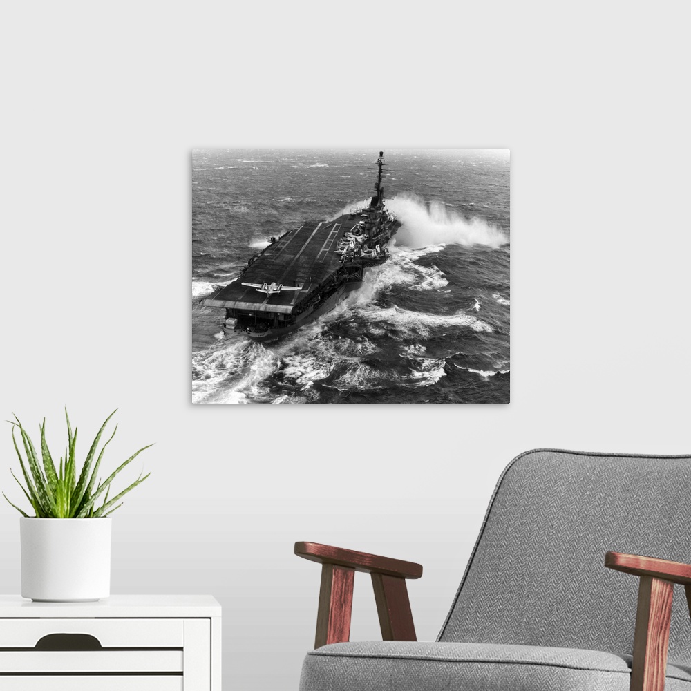 A modern room featuring Aircraft carrier USS Essex (CVA-9) taking spray over the bow while steaming in heavy seas.