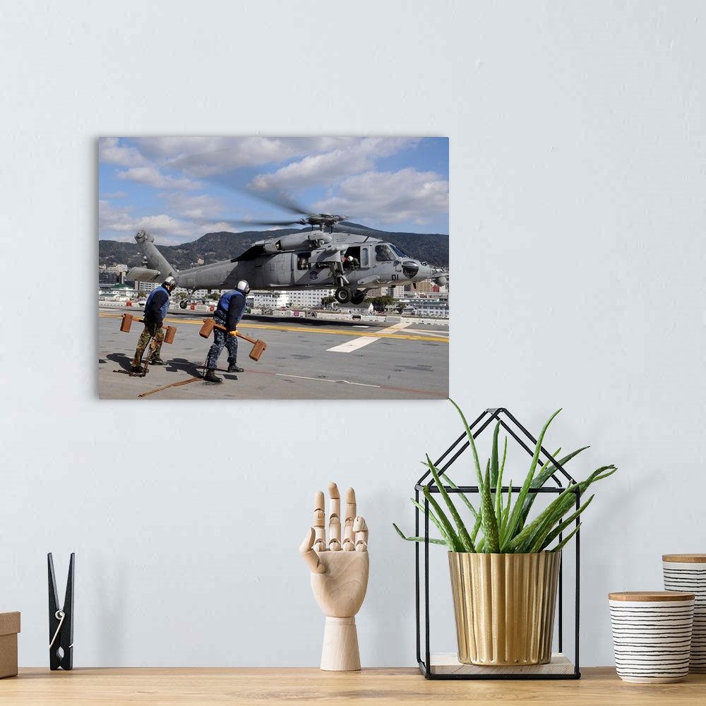 A bohemian room featuring Airmen prepare to chock and chain an MH-60S Sea Hawk helicopter.