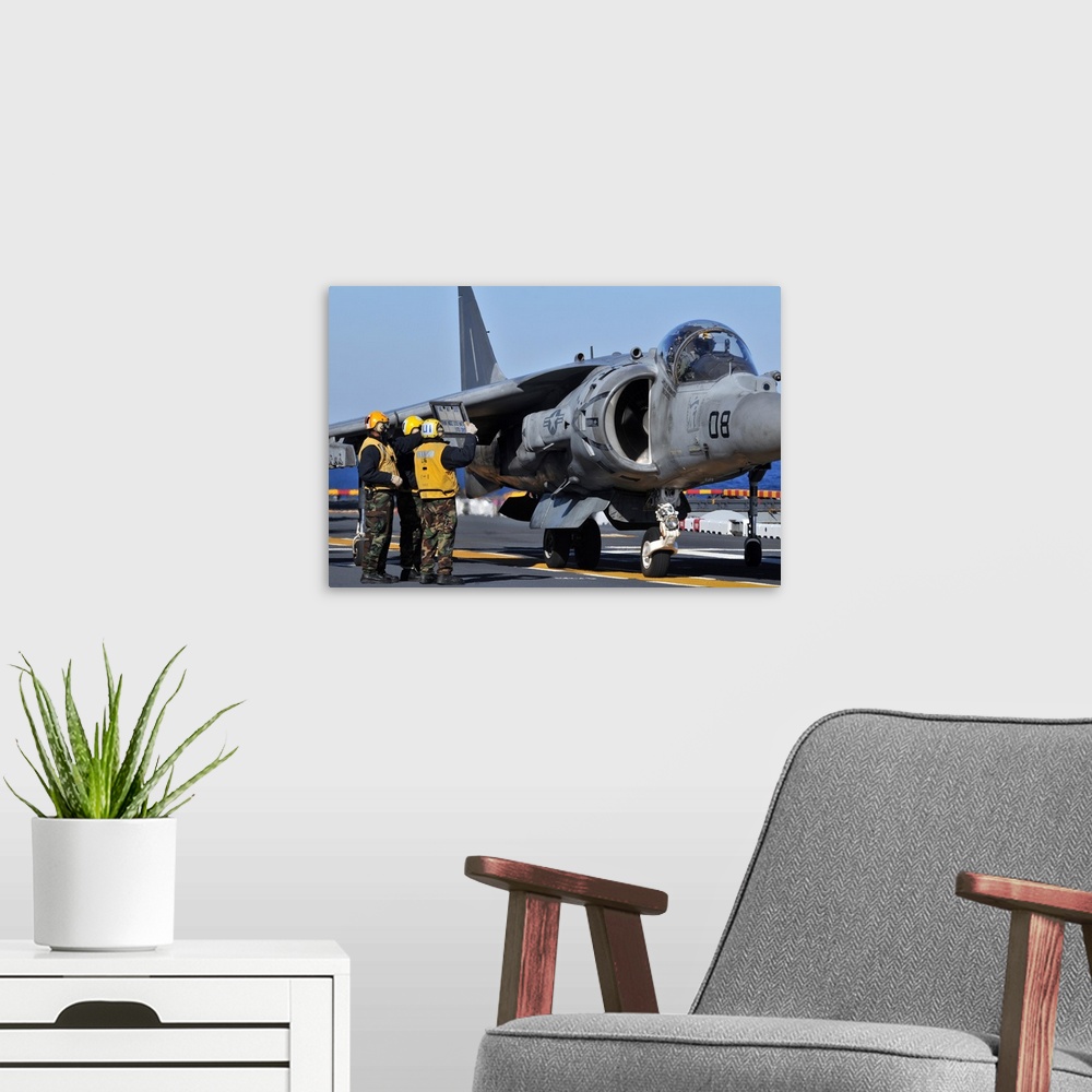 A modern room featuring Airmen show flight information to an AV-8B Harrier pilot.