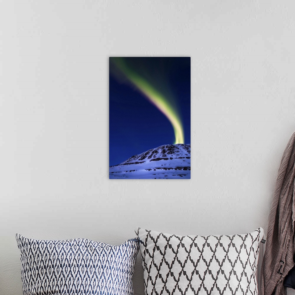 A bohemian room featuring A magnificent display of aurora borealis shooting up from Toviktinden Mountain in Troms County, N...
