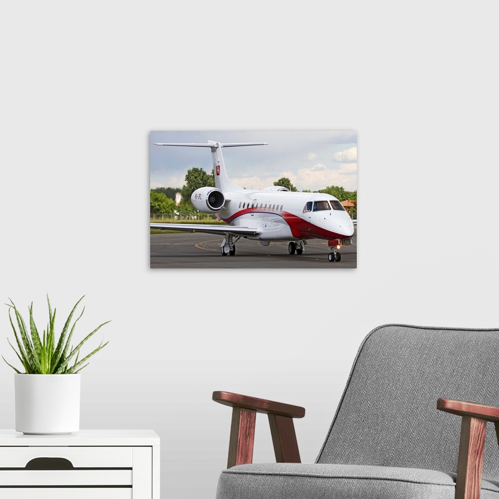 A modern room featuring An Embraer Legacy 600 private jet taxiing at Turin Airport, Italy.