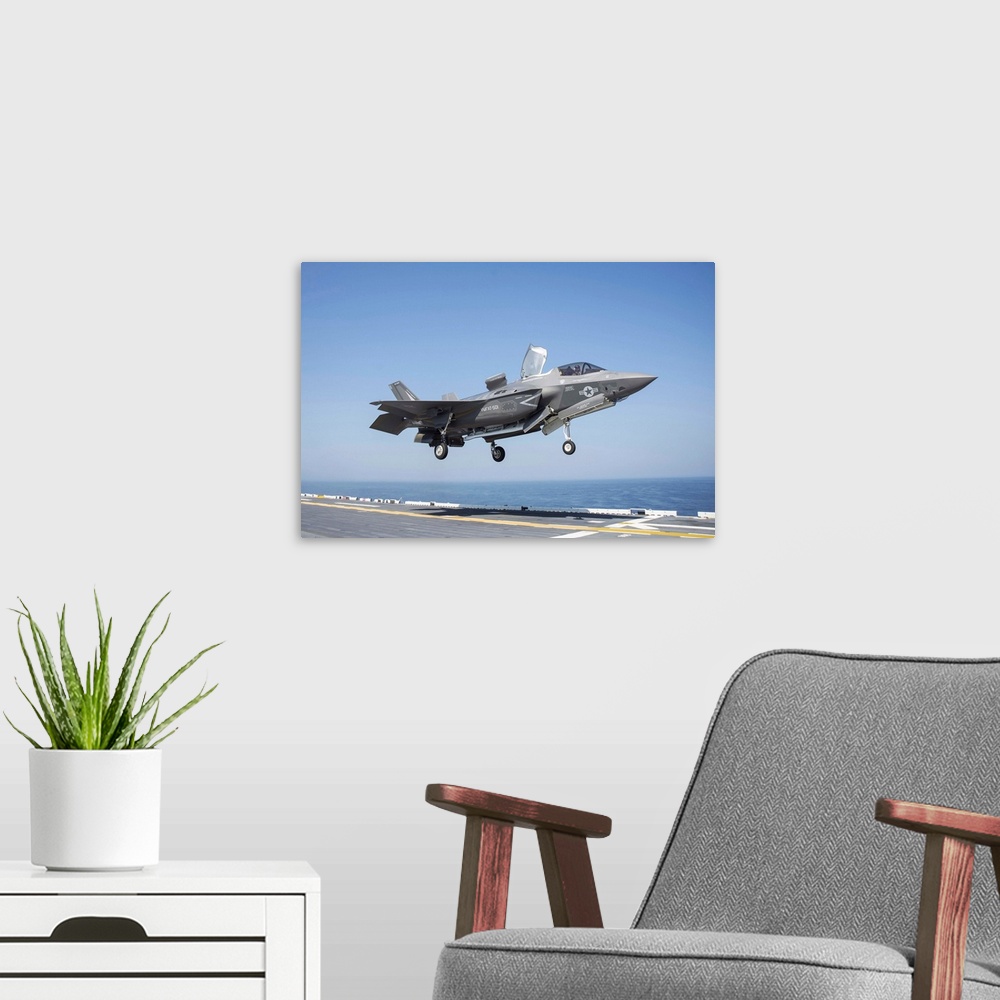 A modern room featuring An F-35B Lighting II lands on the flight deck of USS Wasp.