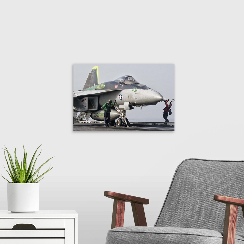 A modern room featuring A U.S. Navy F/A-18 Super Hornet assigned to Squadron VFA-105 is ready to launch from a catapult a...