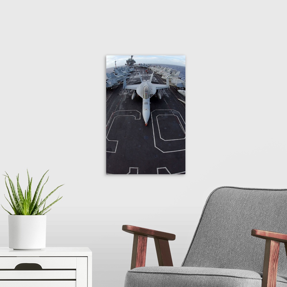 A modern room featuring An F/A-18F Super Hornet of Strike Fighter Squadron 102 parked on the bow of the USS Kitty Hawk.