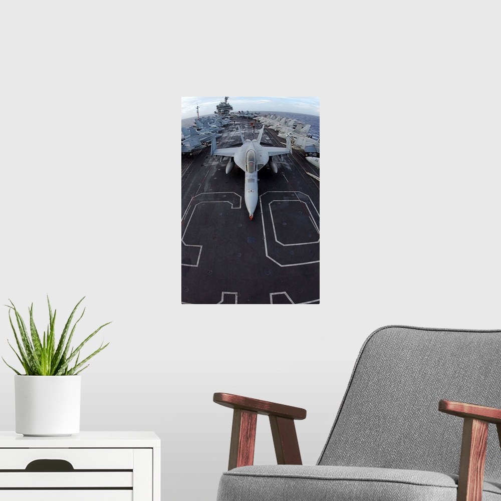 A modern room featuring An F/A-18F Super Hornet of Strike Fighter Squadron 102 parked on the bow of the USS Kitty Hawk.