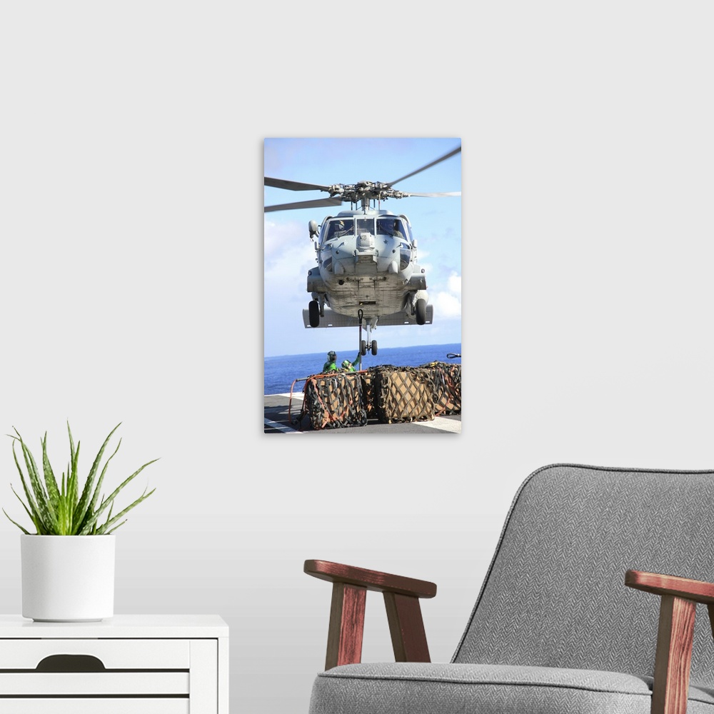A modern room featuring An HH-60H Sea Hawk helicopter picks up supplies from the flight deck.