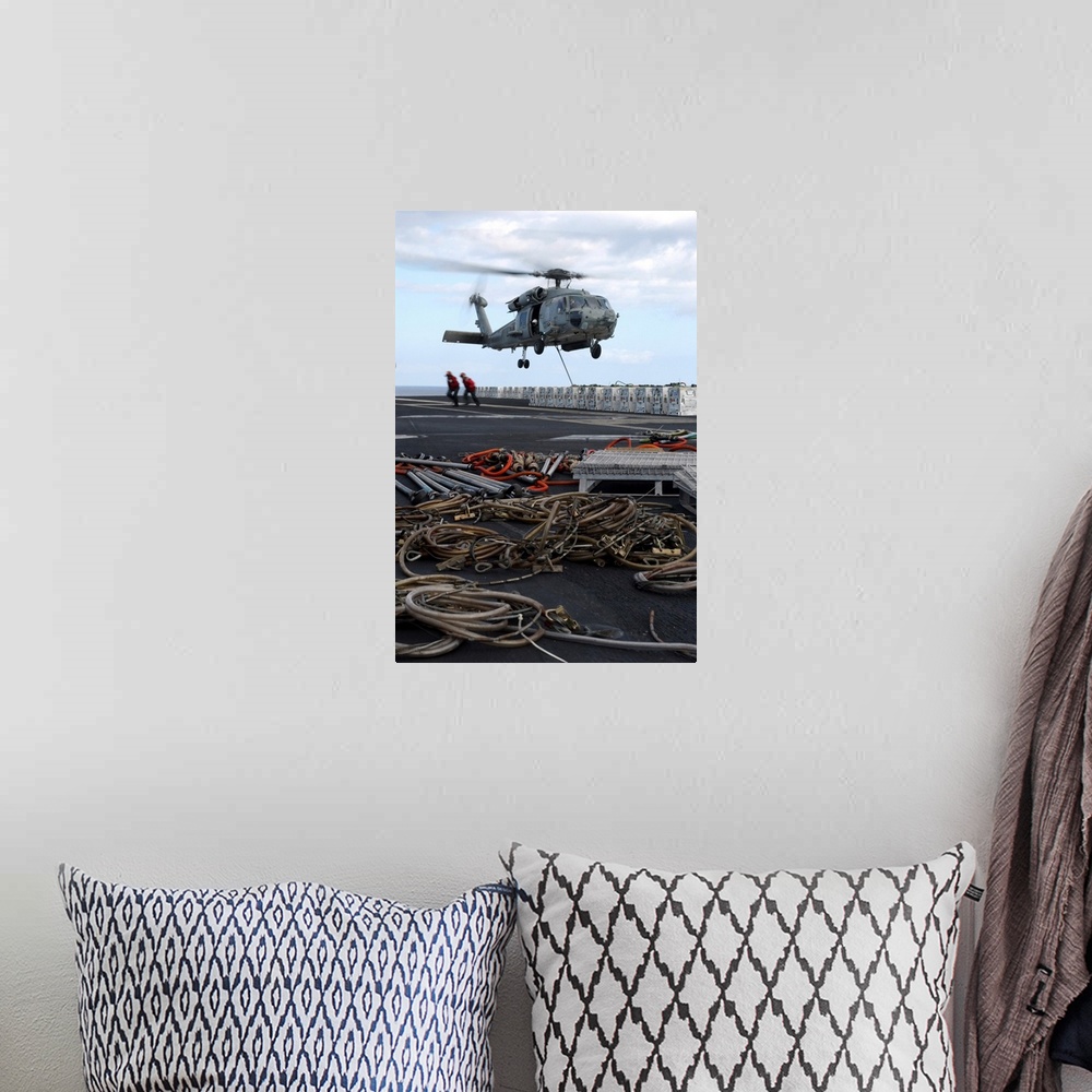 A bohemian room featuring An HH-60H Seahawk helicopter prepares to lift a crate of ordnance.