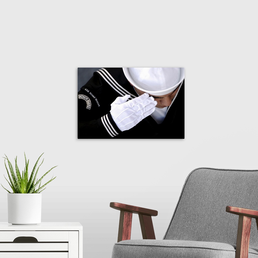 A modern room featuring An Honor Guard member renders a salute during a burial at sea ceremony