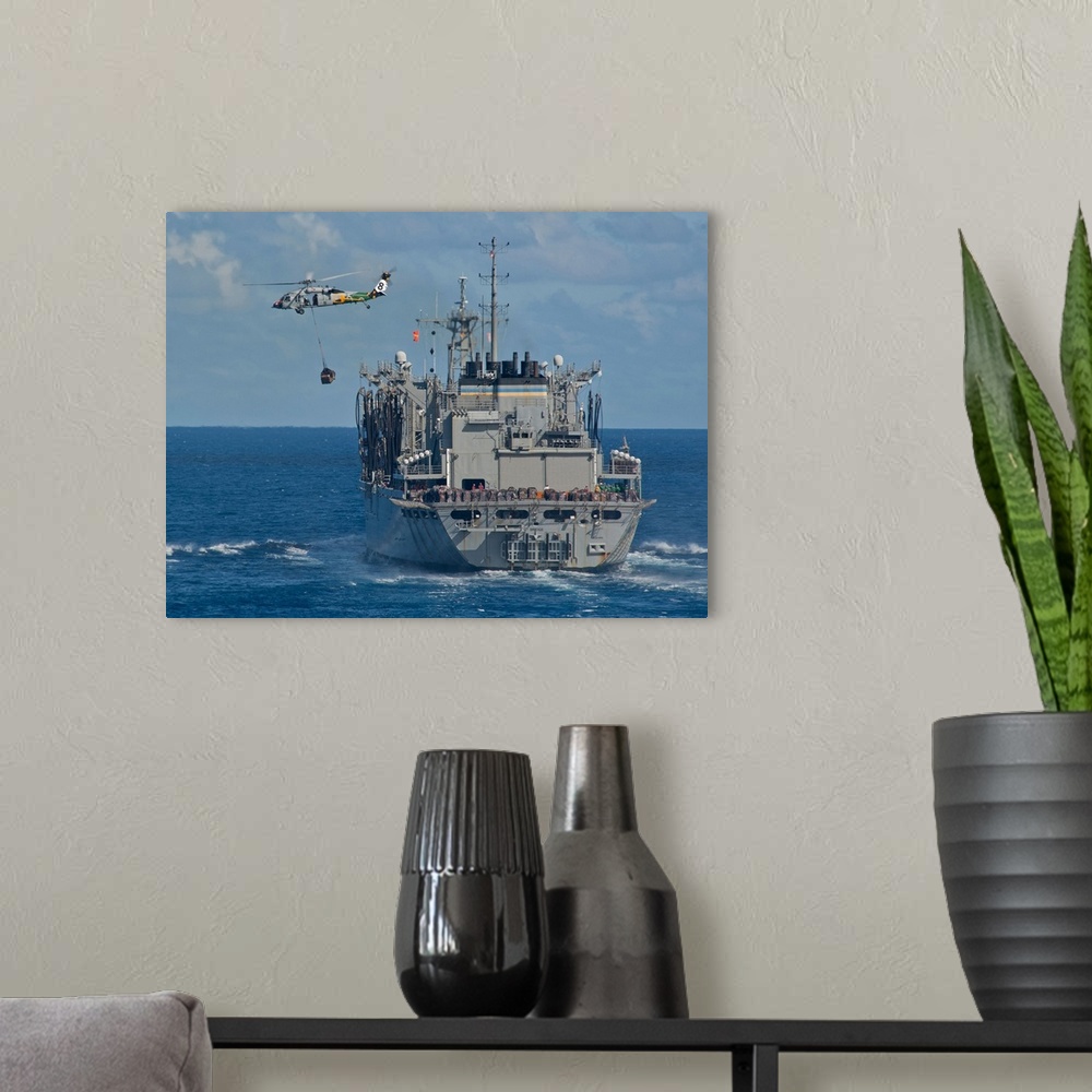 A modern room featuring An MH-60S Sea Hawk conducts a vertical replenishment with USNS Bridge.