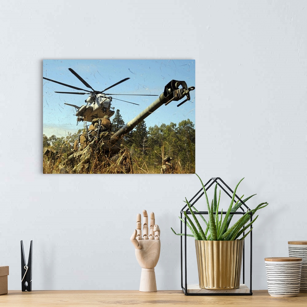 A bohemian room featuring An MH53E Sea Stallion helicopter preparing to lift an M777 105mm lightweight Howitzer