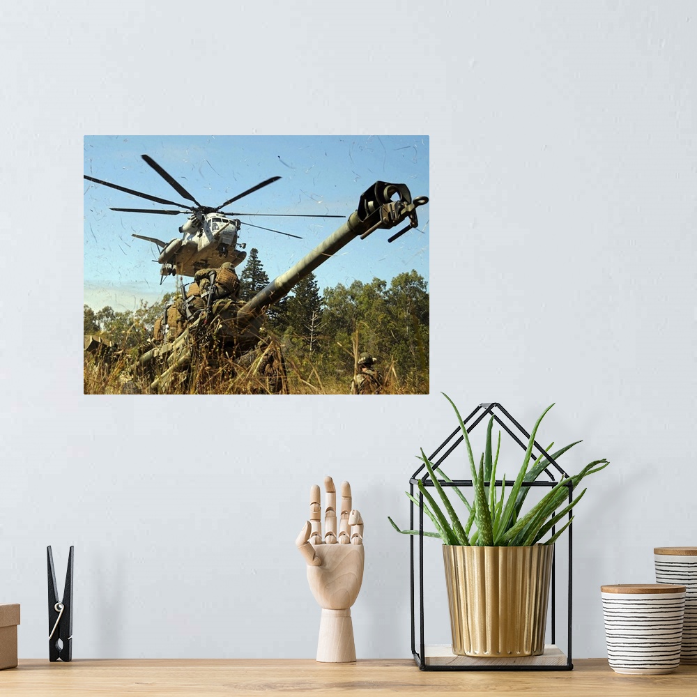 A bohemian room featuring An MH53E Sea Stallion helicopter preparing to lift an M777 105mm lightweight Howitzer
