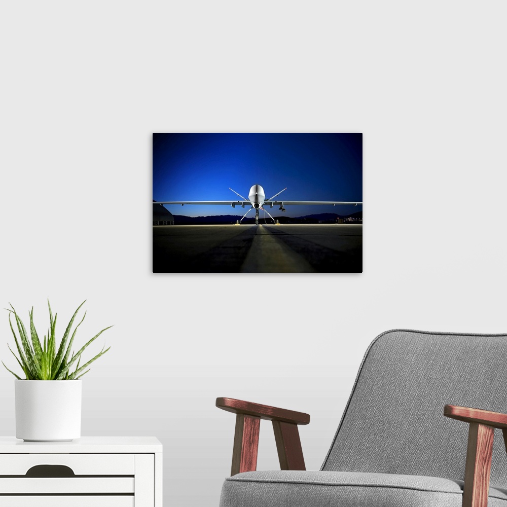 A modern room featuring Photograph of airplane on runway with mountain silhouette in the distance at night.