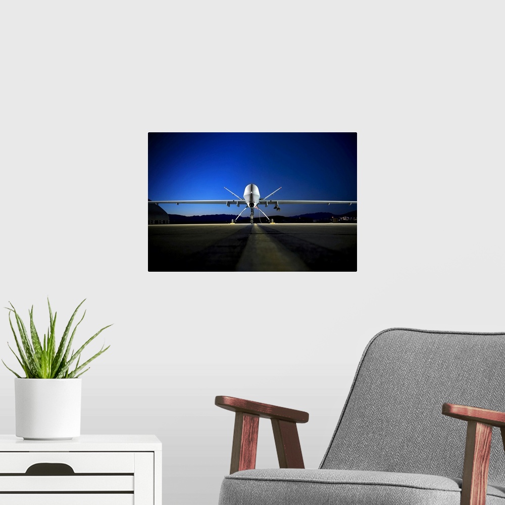 A modern room featuring Photograph of airplane on runway with mountain silhouette in the distance at night.