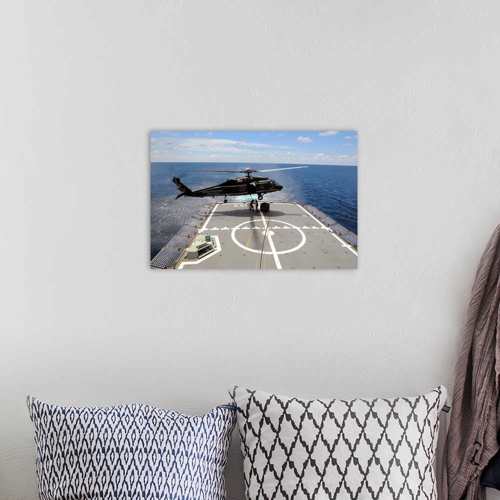 A bohemian room featuring An SH-60F Sea Hawk helicopter lowers pallets onto HMAS Ballarat.