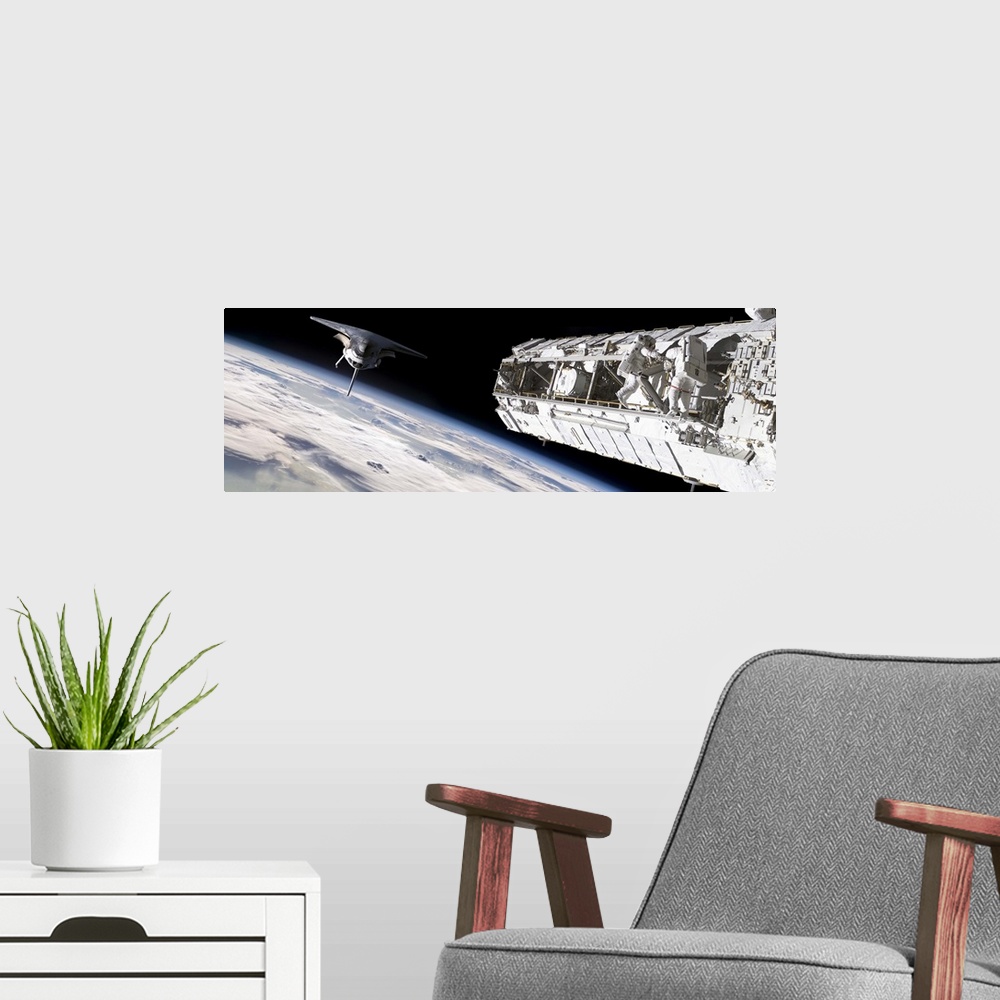 A modern room featuring Astronauts work on a space station while a space shuttle approaches.