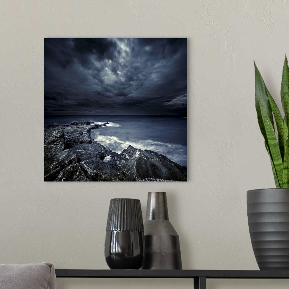 A modern room featuring Black rocks protruding through rough seas with stormy clouds, Crete, Greece.