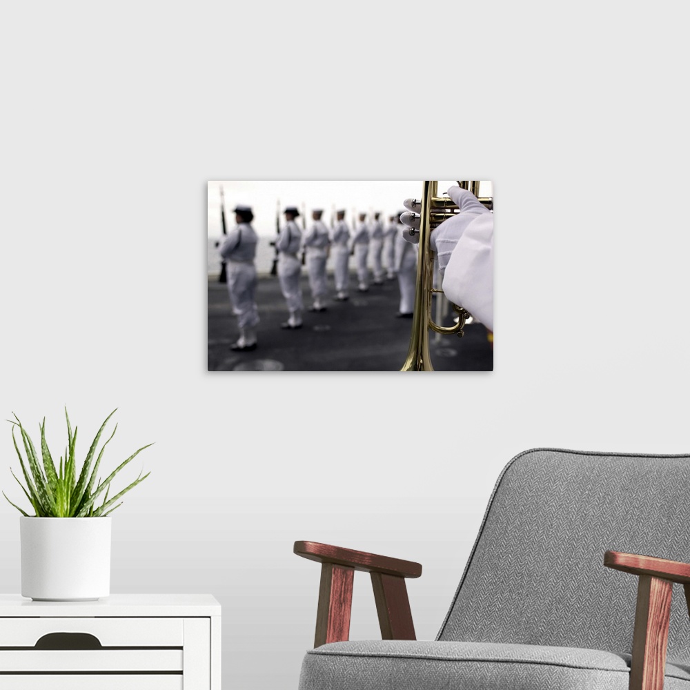 A modern room featuring Ceremonial Honor Guard members stand at port arms during a burial at sea ceremony
