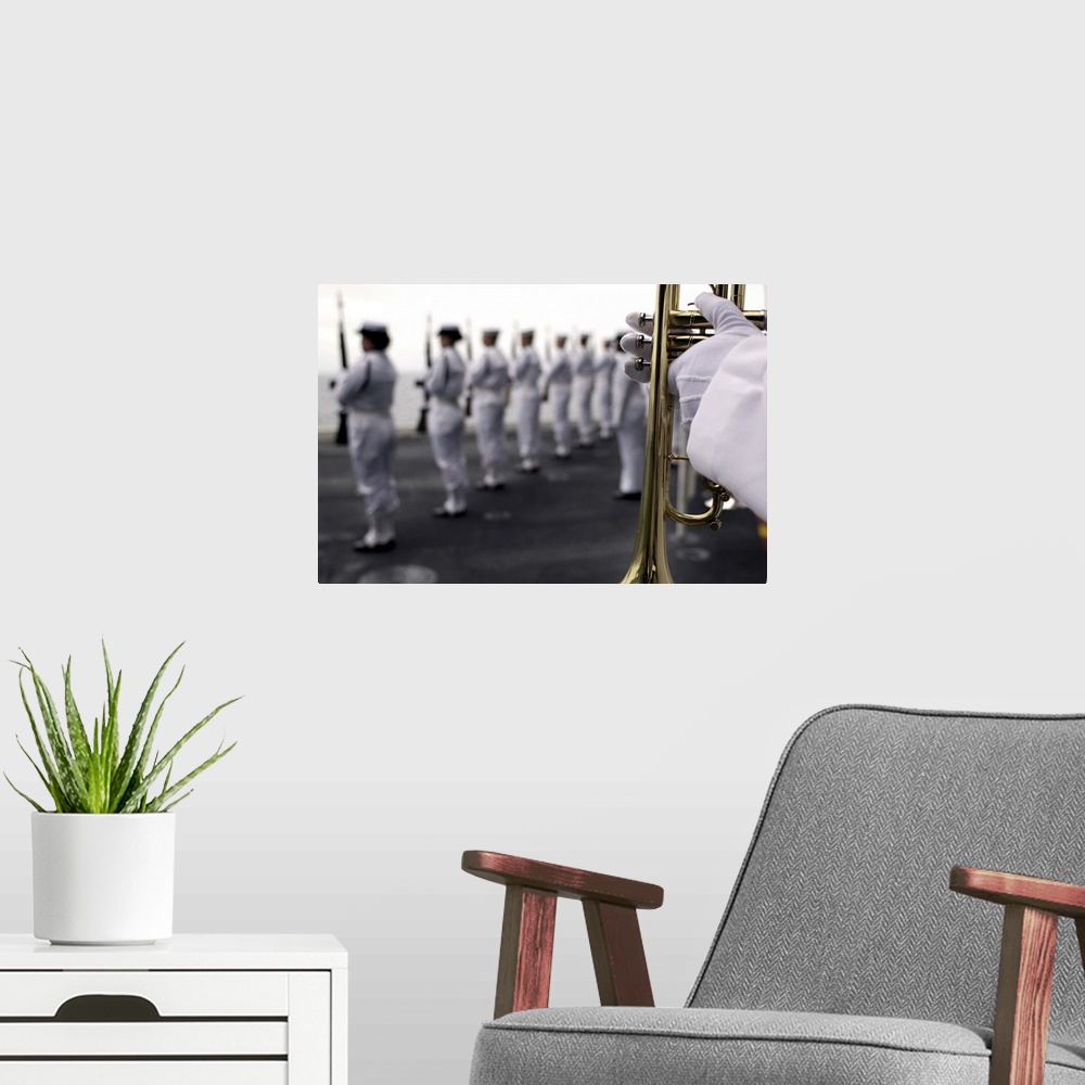 A modern room featuring Ceremonial Honor Guard members stand at port arms during a burial at sea ceremony
