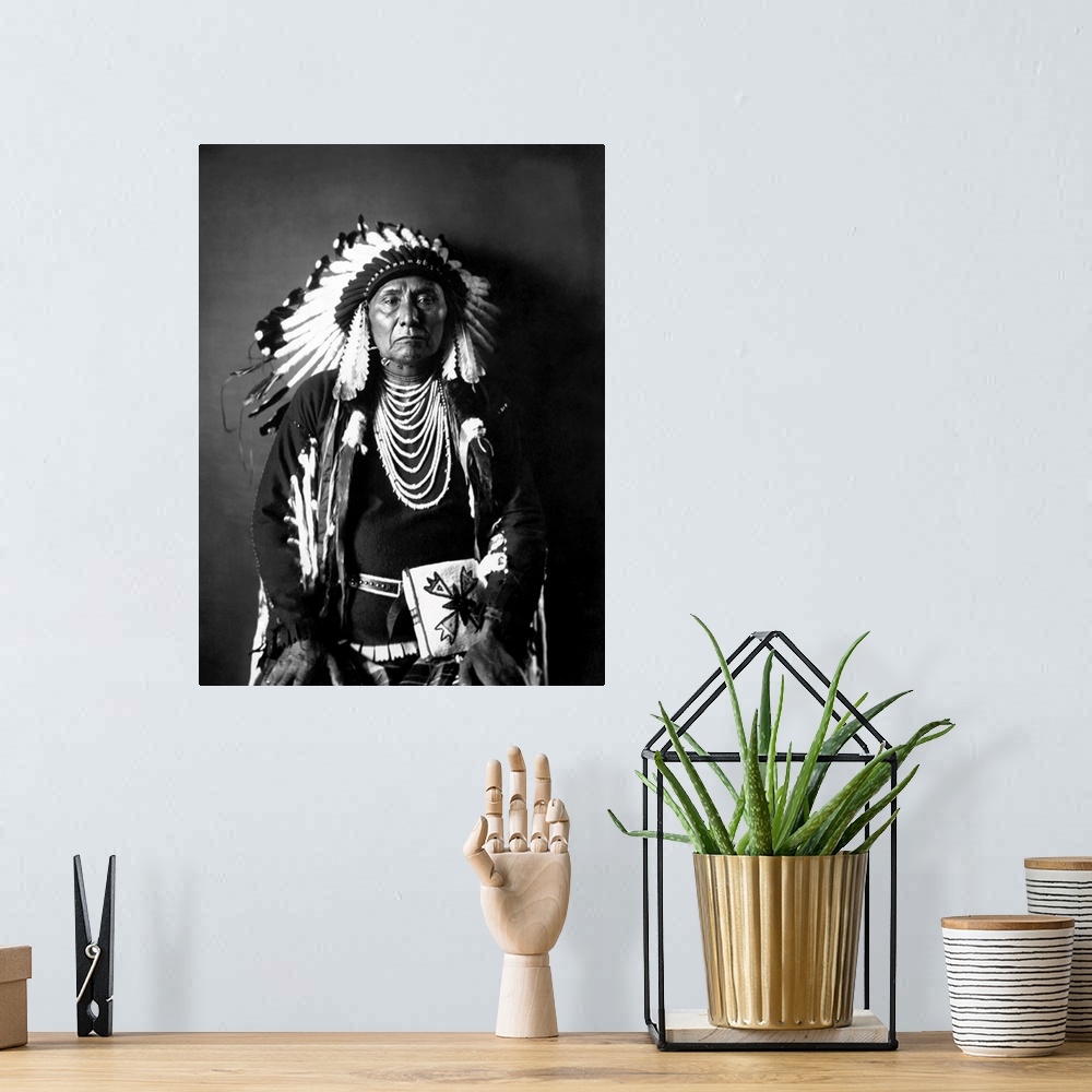 A bohemian room featuring Chief Joseph of the Nez Perce tribe in a black and white seated portrait in full traditional trib...