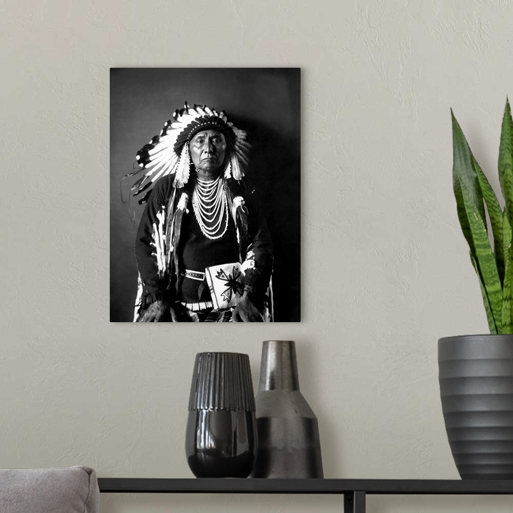 A modern room featuring Chief Joseph of the Nez Perce tribe in a black and white seated portrait in full traditional trib...